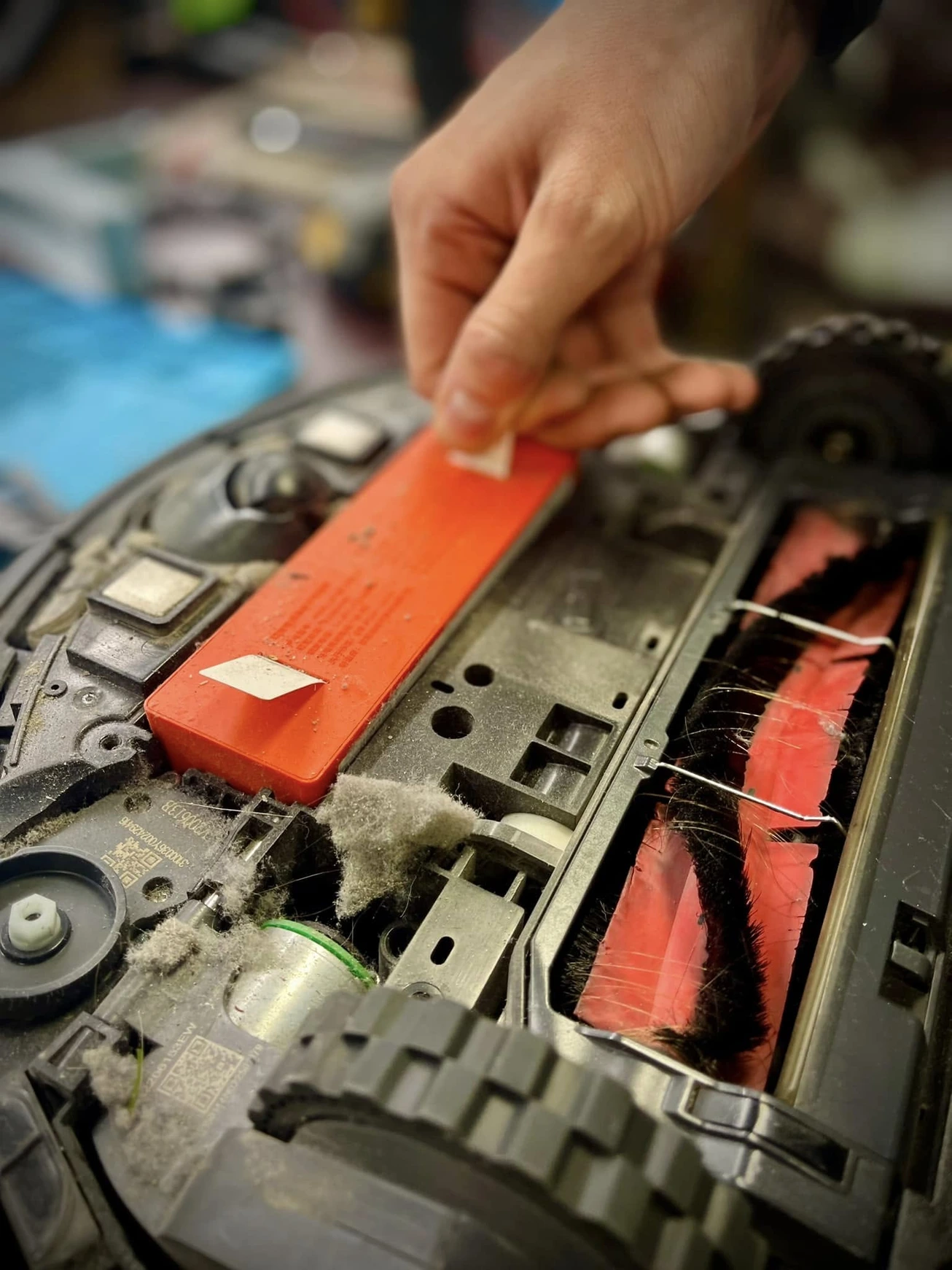 Putekļains robots ar izņemtu izlietoto baterijas moduli.