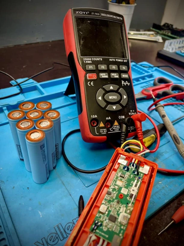 Multimetrs un jaunas 21700 šūnas BMS testēšanas laikā.